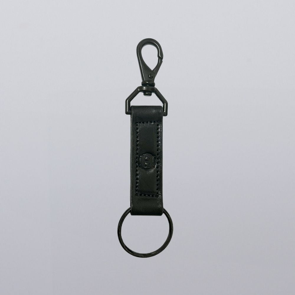 The Handy-Dandy Keychain by Hanks Belts, a handmade leather strap with a metal key ring and swivel clasp clip, is shown against a plain light gray background.