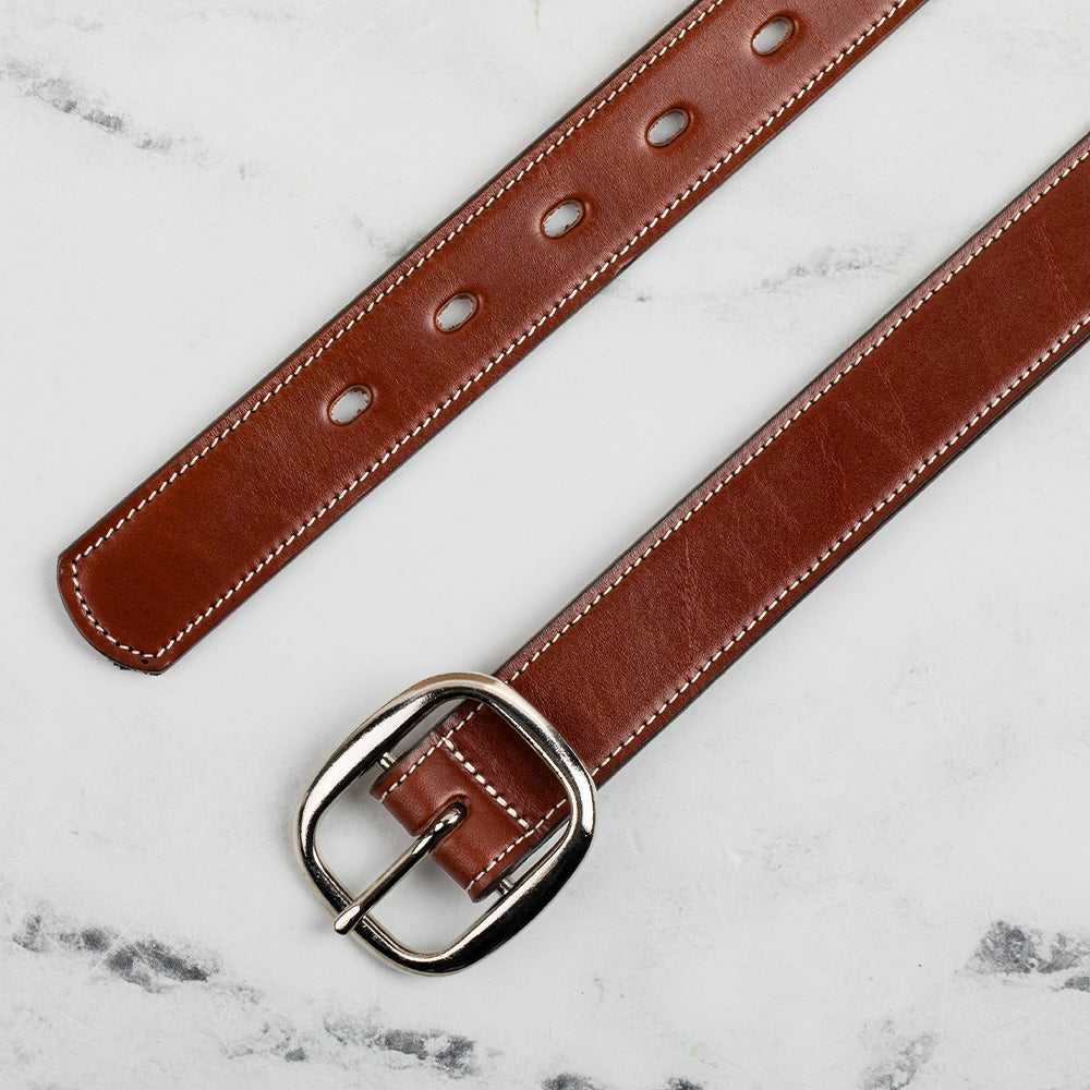 The Eloise by Hanks Belts is a premium women's belt made from vegetable-tanned leather, featuring white stitching and a silver center bar buckle, displayed flat on white marble.