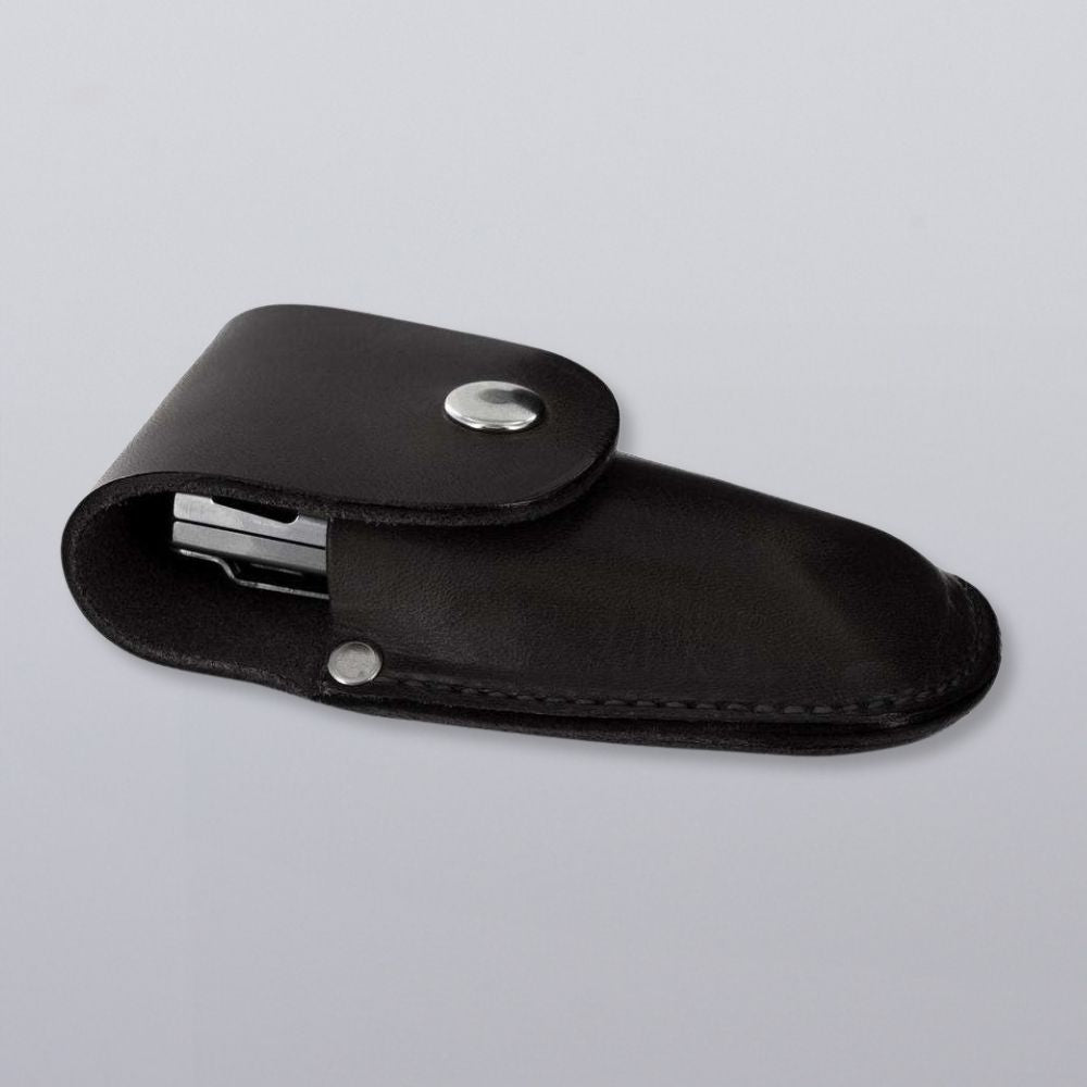 The Canyon Utility Sheath and Mag Case by Hanks Belts—a black bridle leather pouch with a snap button closure—partially reveals a metallic item inside, displayed on a plain light gray background.