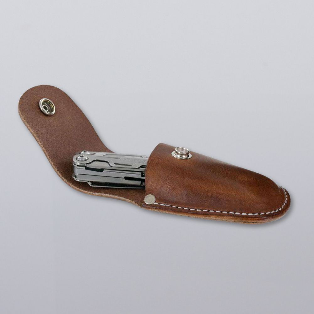 A Canyon Utility Sheath and Mag Case by Hanks Belts in brown bridle leather with white stitching and snap closure, shown on a gray background holding a multitool. Handcrafted in the USA for lasting quality.
