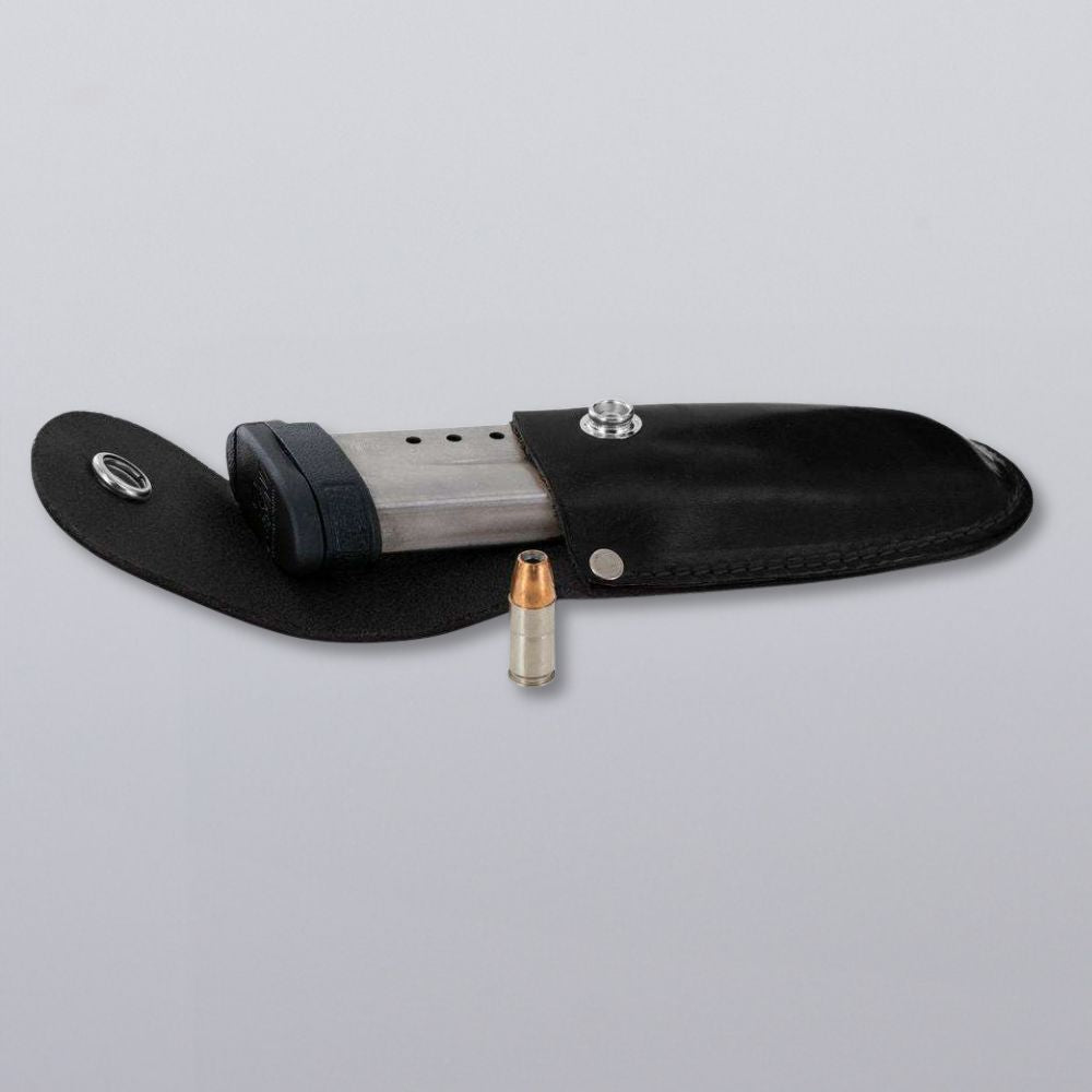 The Hanks Belts Canyon Utility Sheath and Mag Case, made of handcrafted bridle leather, holds a metal pistol magazine with the pouch open and a single bullet upright in front, displayed on a plain gray background.