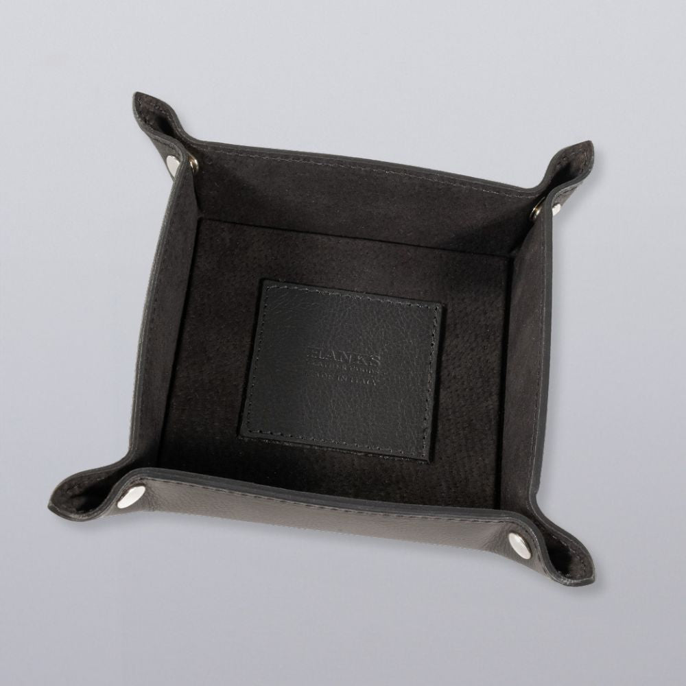 The Hanks Belts Italian Compact Valet Tray, crafted from Italian leather with raised edges and silver snaps, sits on a light gray surface. A matching black leather card rests in this elegant catchall—ideal for organizing essentials.