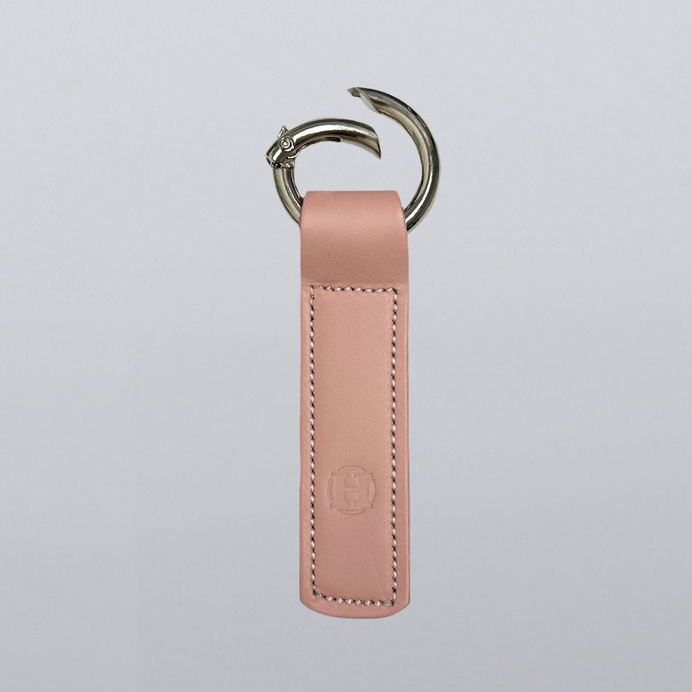The Superior Keychain by Hanks Belts features pink leather in a rectangle shape, neat stitching, a horse head open gate keyring, and a subtle embossed logo near the bottom. The background is light gray.