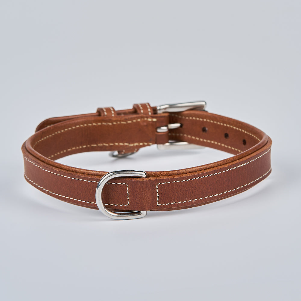 The Hanks Belts Kodak Bison Collar, made of brown bison leather with white stitching, a silver buckle, and metal D-ring, is displayed on a light gray background.