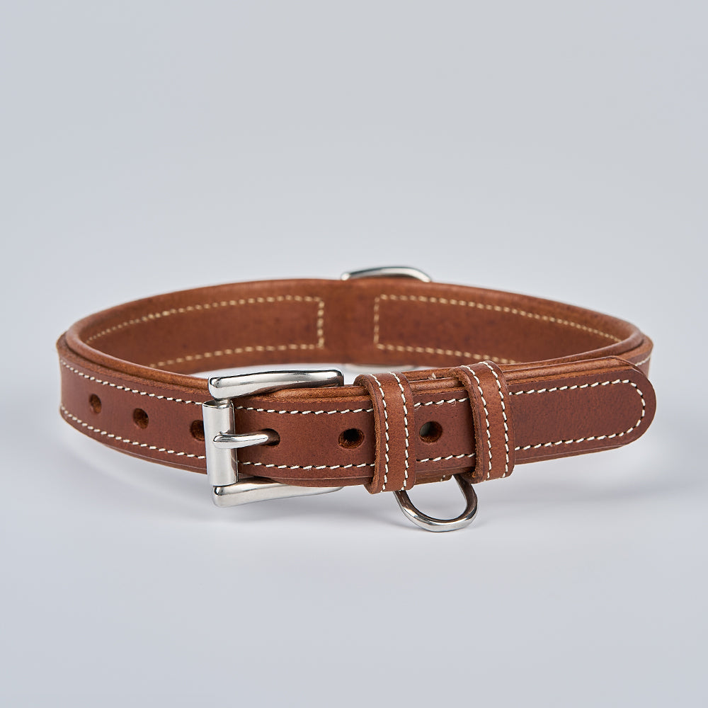 The Kodak Bison Collar by Hanks Belts features brown bison leather, white stitching, a silver buckle, and a metal D-ring, shown on a plain light gray background.