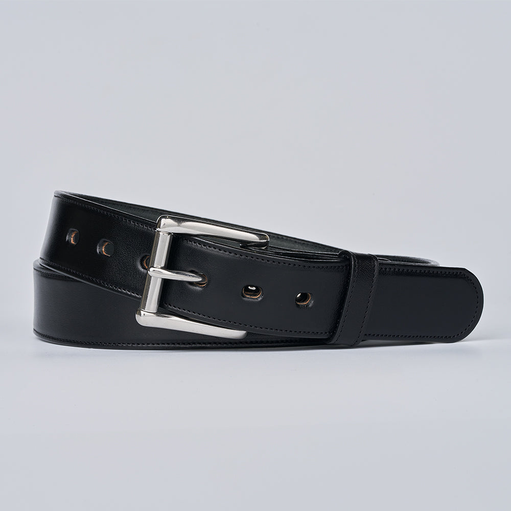 The Canyon by Hanks Belts is a black handcrafted English bridle leather belt with a silver buckle, coiled neatly on a plain light gray background.