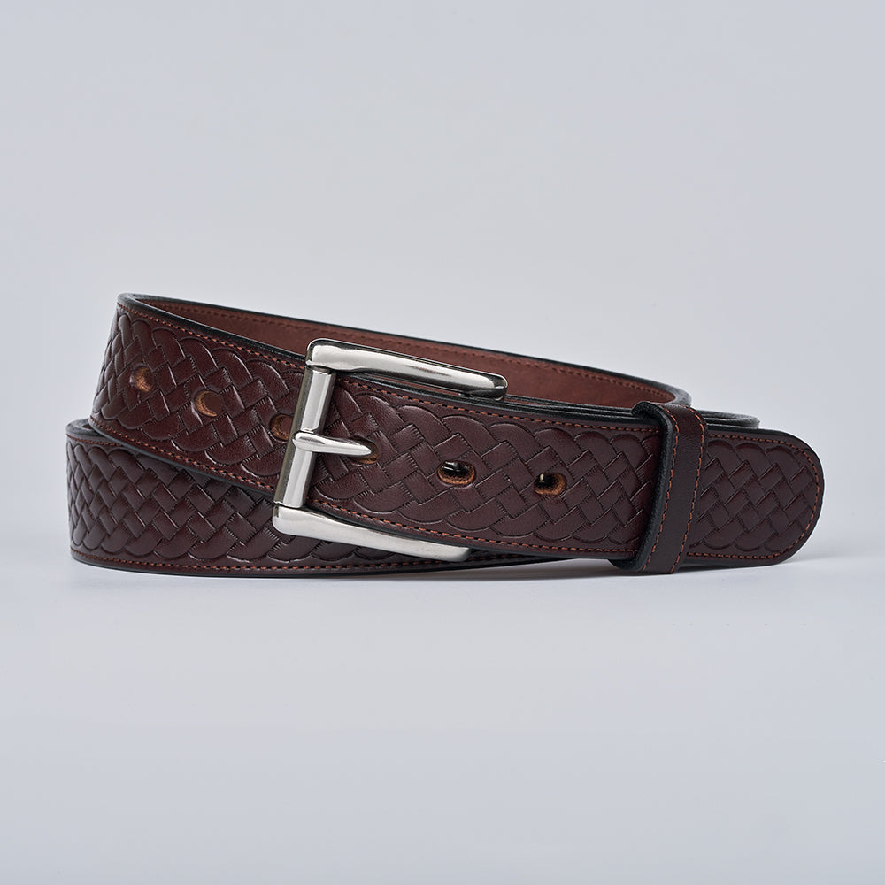 The Classic Basket Weave by Hanks Belts—a brown leather belt with a silver buckle—is coiled neatly against a plain light gray background.