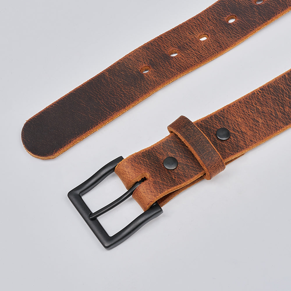 A close-up of The Crazy Horse belt by Hanks Belts, crafted from Water Buffalo leather with a black metal buckle and multiple adjustment holes, shown laid flat on a light gray background.