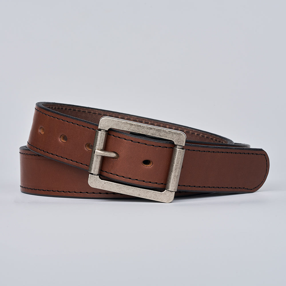 The Double Roller by Hanks Belts is a brown full-grain leather belt with visible stitching and a silver rectangular buckle, coiled and displayed on a plain light gray background.