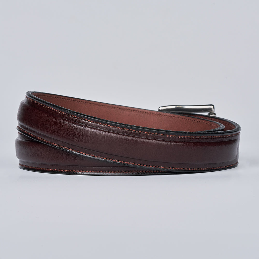 The Esquire Raised by Hanks Belts: a coiled brown premium leather belt with visible stitching and a silver buckle, shown on a plain light gray background.