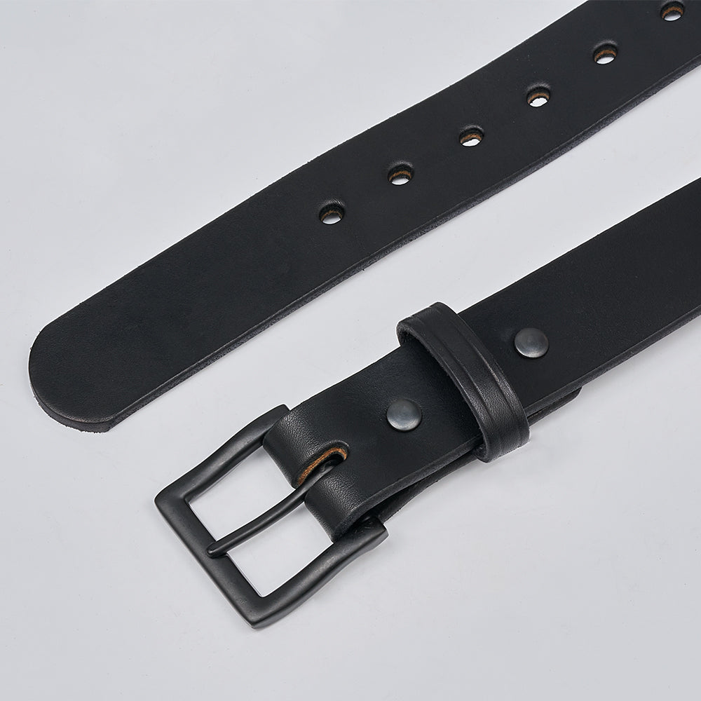 A close-up of The Everyday belt by Hanks Belts, featuring durable black leather, a matte black metal buckle, and multiple adjustment holes, displayed on a light gray surface.