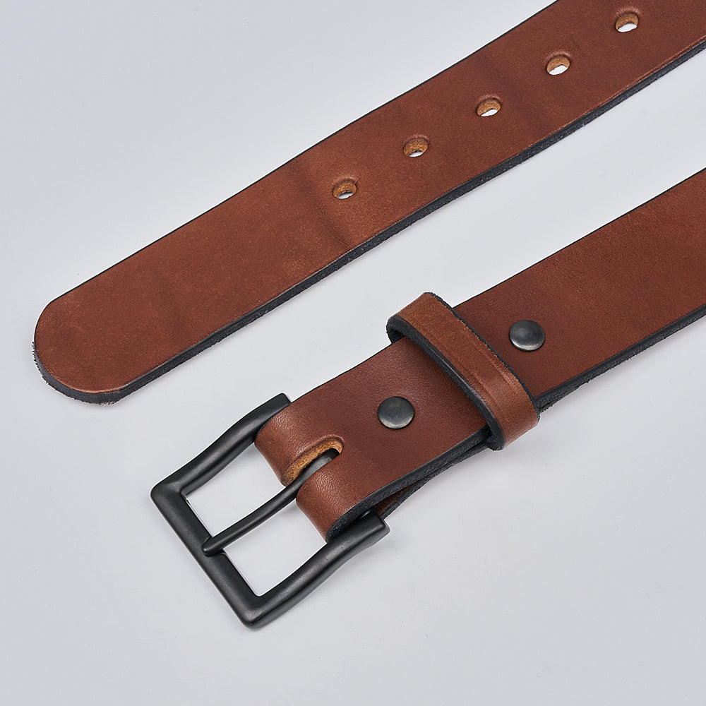 The Everyday belt by Hanks Belts features full grain leather, a matte black buckle, multiple holes, and black screws, displayed flat on a light gray surface.