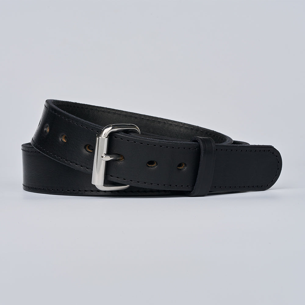 The Gunner Stitched by Hanks Belts—a black full-grain leather gun belt with a silver buckle, visible edge stitching, and evenly spaced holes—is coiled neatly on a plain light gray background.