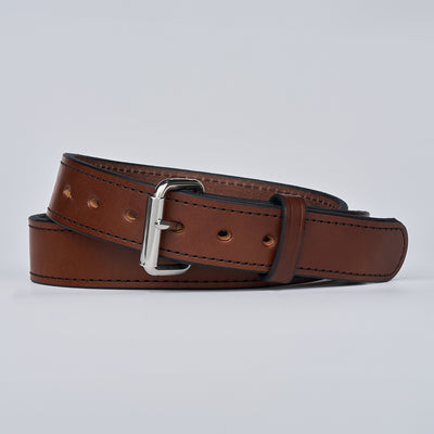 The Gunner Stitched by Hanks Belts is a full-grain leather CCW belt with black stitching, multiple holes, and a silver metal buckle, coiled loosely on a plain light background.