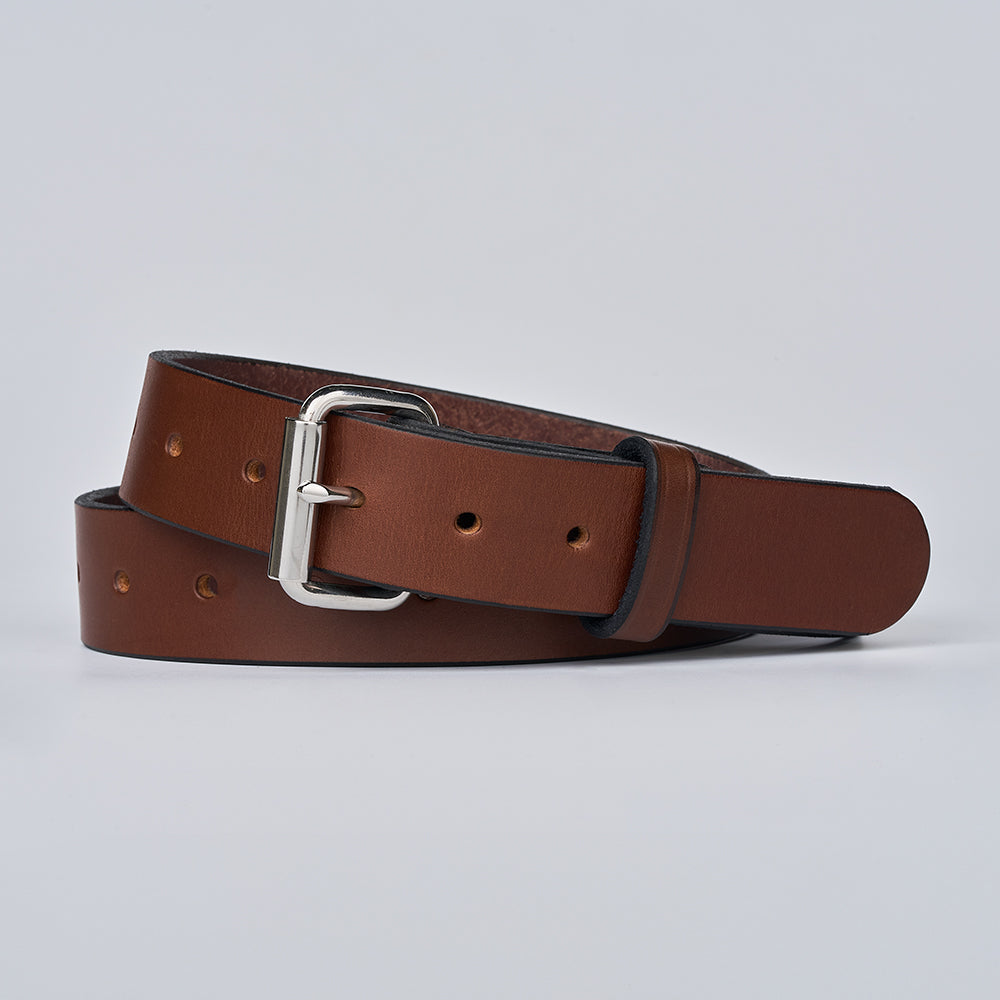 The Gunner Utility by Hanks Belts is a brown leather gun belt with a silver buckle, shown coiled on a light gray background. It features evenly spaced holes, a smooth finish, and is crafted for secure everyday carry.