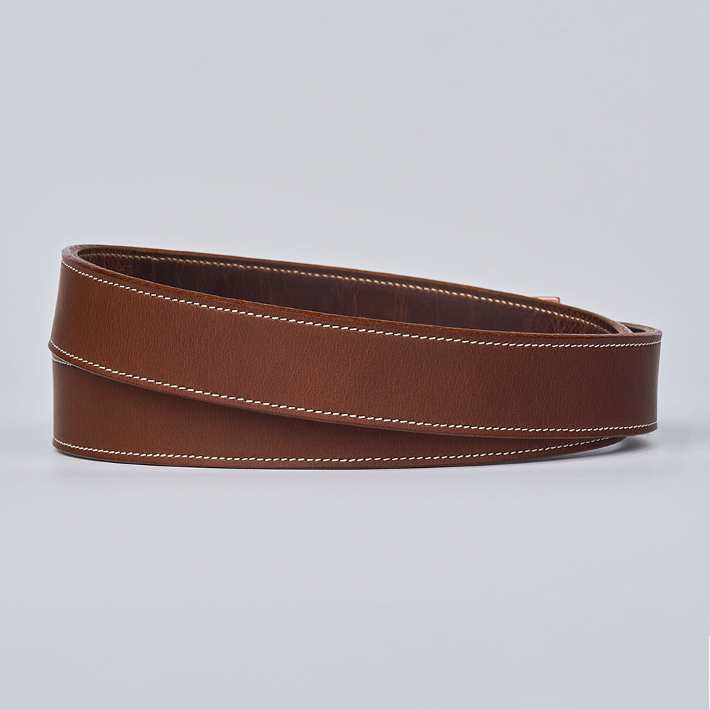 The Heritage Bison belt by Hanks Belts, crafted from brown bison leather with prominent white edge stitching, is displayed coiled on a light gray background.