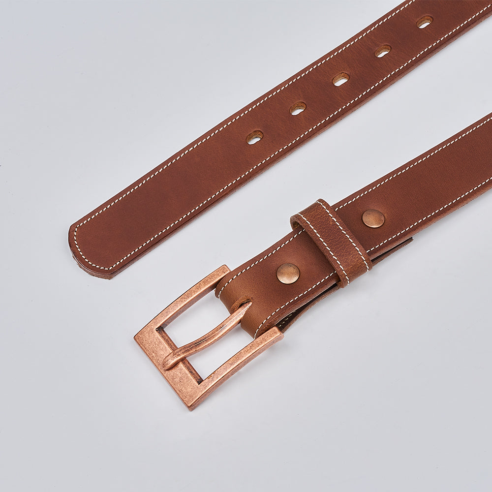The Heritage Bison by Hanks Belts features rugged bison leather, white stitching, gold-tone metal buckle, and round rivets, displayed on a light gray background.