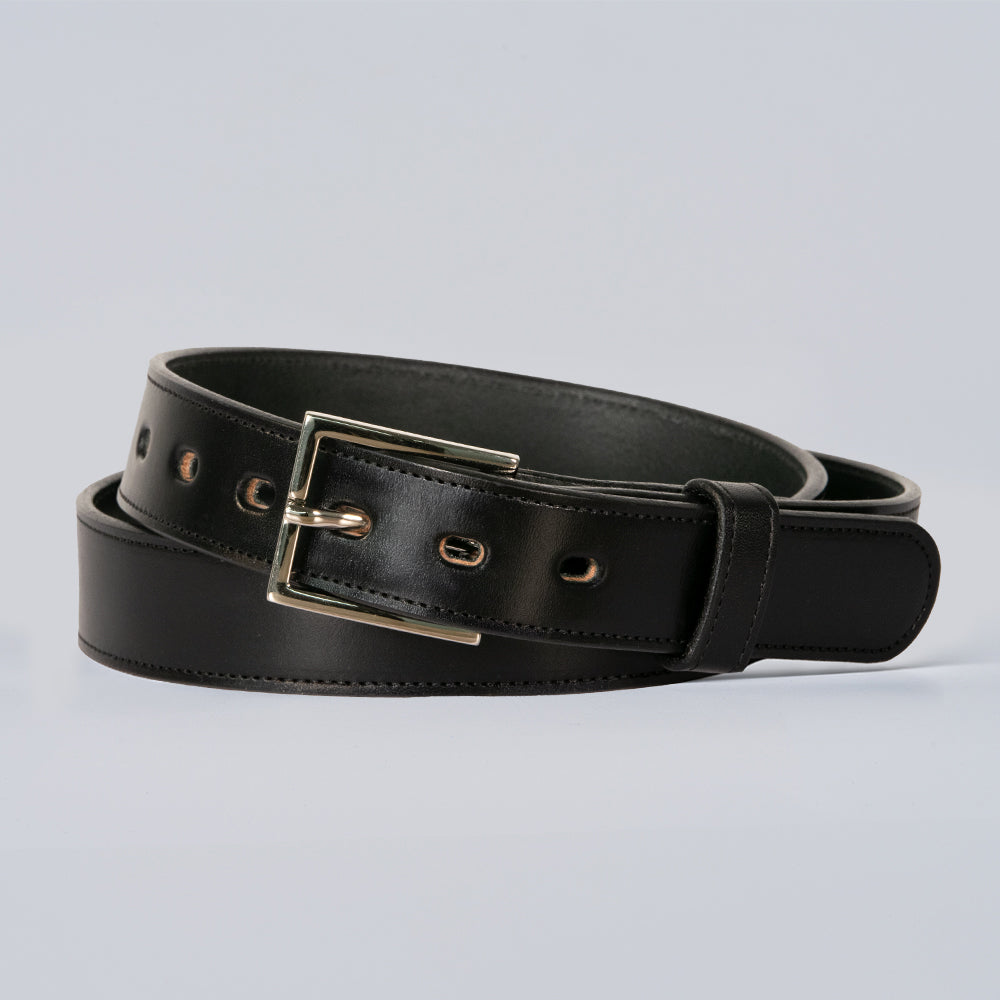 The Ledger black leather belt by Hanks Belts, featuring a silver rectangular buckle, is coiled neatly against a plain light background.