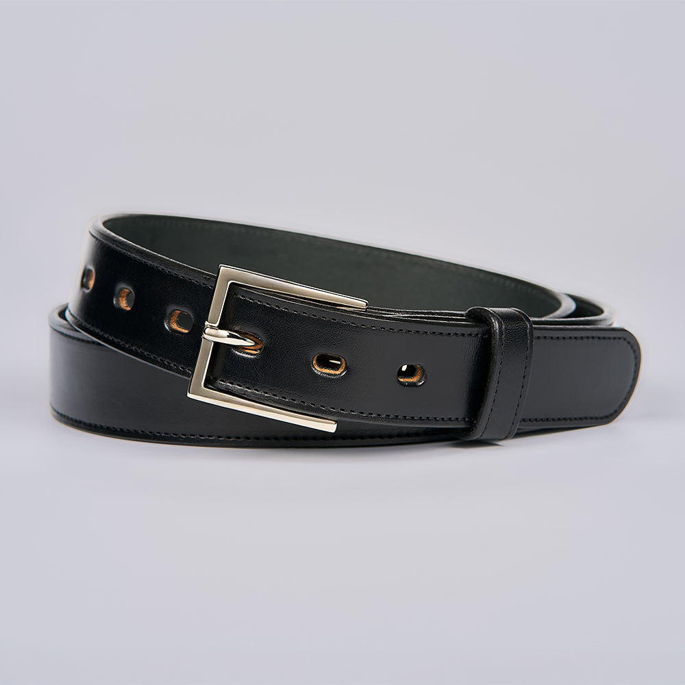The Ledger by Hanks Belts is a men's dress belt in black English bridle leather, featuring gold-toned metal eyelets and a polished silver rectangular buckle, shown coiled neatly on a light gray background.