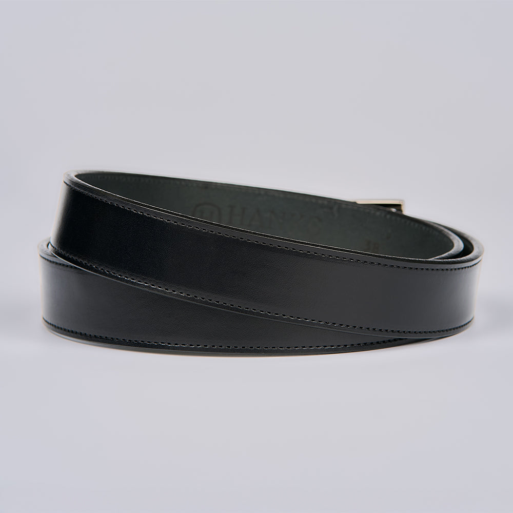 The Ledger by Hanks Belts, a men's dress belt crafted from English bridle leather with visible edge stitching, is coiled in a circular shape on a light gray background.