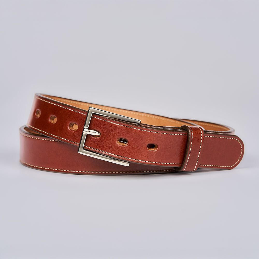 The Ledger by Hanks Belts is a men's brown English bridle leather belt with white stitching and a silver rectangular buckle, shown coiled neatly on a plain light gray background.