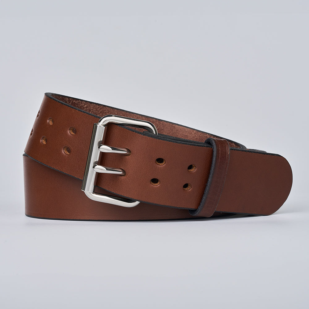 The Marshall by Hanks Belts—a brown leather garrison-style belt with a silver double-prong buckle—neatly rolled on a plain light gray background.