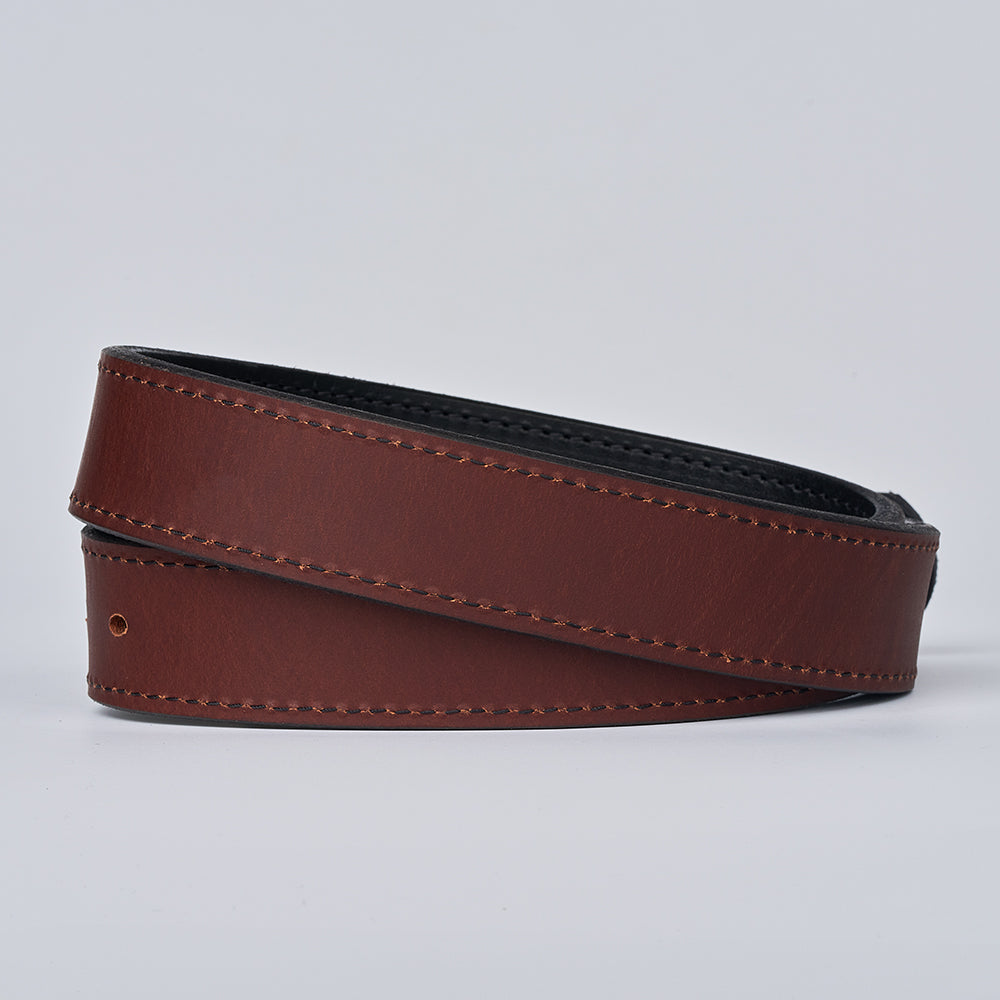 The Reversible by Hanks Belts is a coiled brown leather belt with visible stitching and a black inner lining, shown against a plain light gray background.