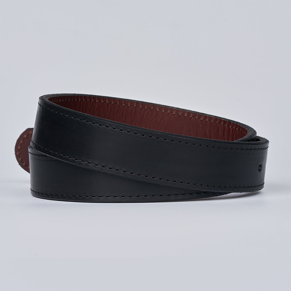 The Hanks Belts "The Reversible" black leather belt, featuring a brown inner lining, is coiled in a spiral on a plain white background.