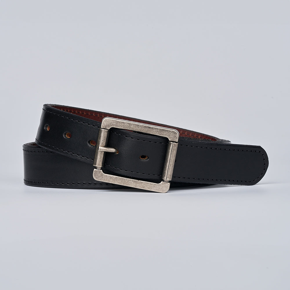 The Reversible by Hanks Belts is a black leather belt with a rectangular silver buckle, shown coiled neatly and facing forward on a plain light gray background.