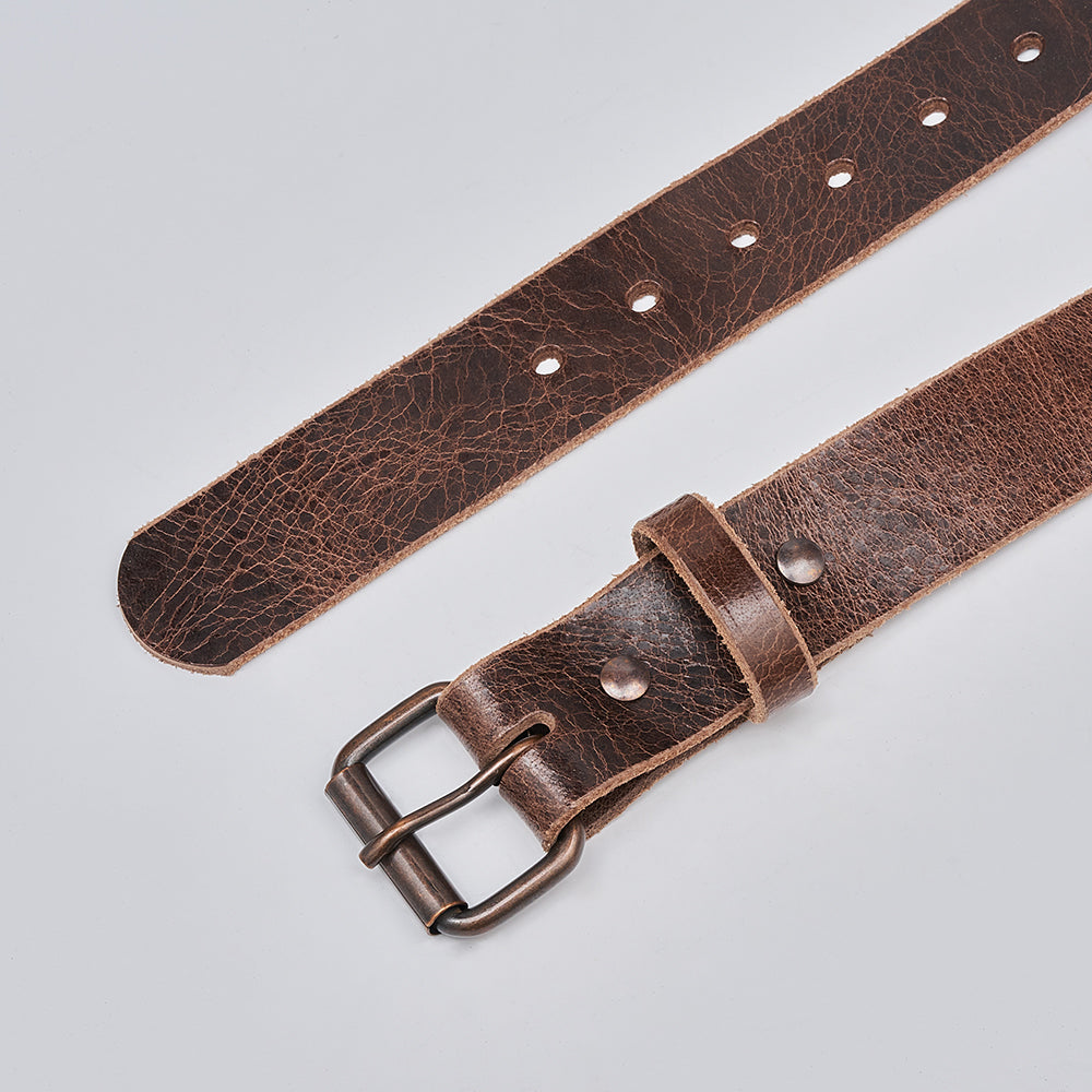 A close-up of The Rustic Glazed leather belt by Hanks Belts highlights its textured surface, metal buckle, belt loop, and multiple adjustment holes against a plain light background.