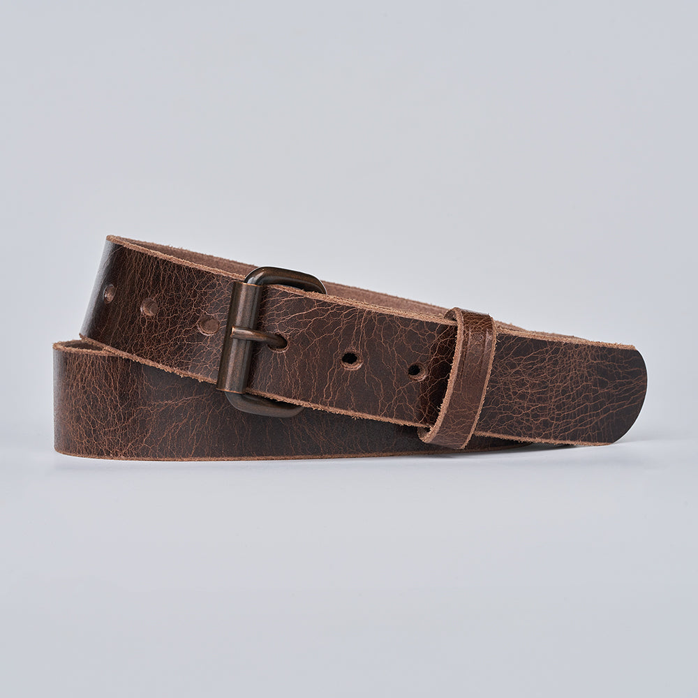 The Rustic Glazed by Hanks Belts features a textured leather finish, metal buckle, and multiple adjustment holes, shown coiled on a light gray background.