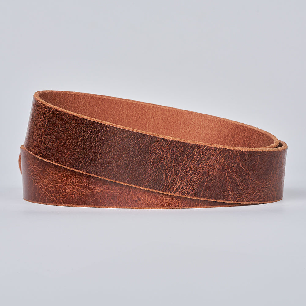 The Rustic Glazed by Hanks Belts—a coiled strip of brown full grain leather with a textured, slightly worn surface—displayed against a plain light gray background.