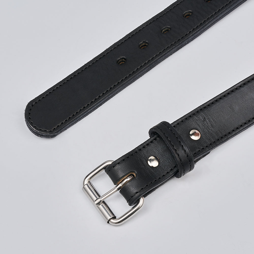 A close-up of Hanks Belts' The Steel Core - 1.5" black leather CCW belt with a silver buckle, lying flat on a light gray surface, shows multiple adjustment holes, visible edge stitching, and firm support for concealed carry.