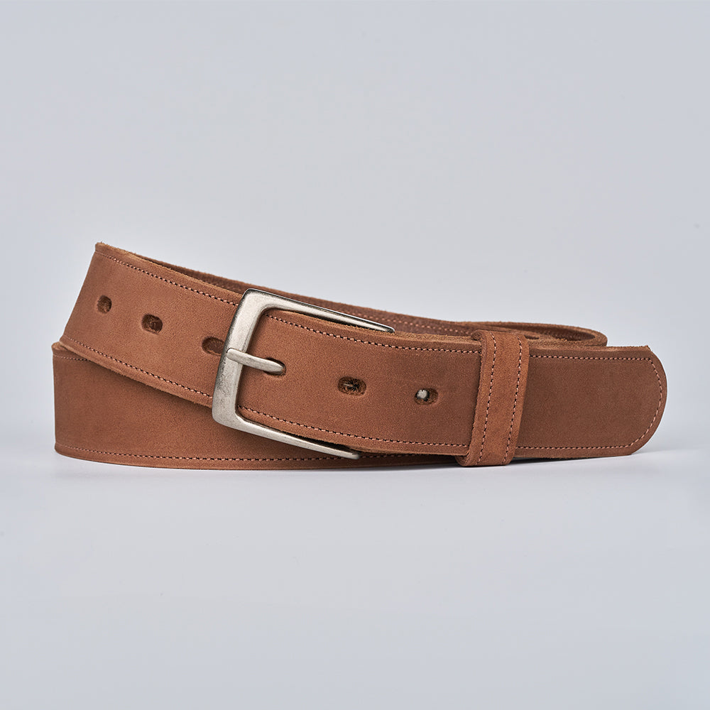 The Suede - 1.5" by Hanks Belts, a brown USA-made suede belt with a silver metal buckle, is shown coiled neatly on a plain light gray background.