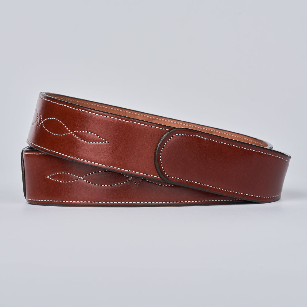 The Teton Tapered by Hanks Belts is a handcrafted, vegetable-tanned leather belt with white stitching and embossed patterns, shown coiled neatly on a plain light background.