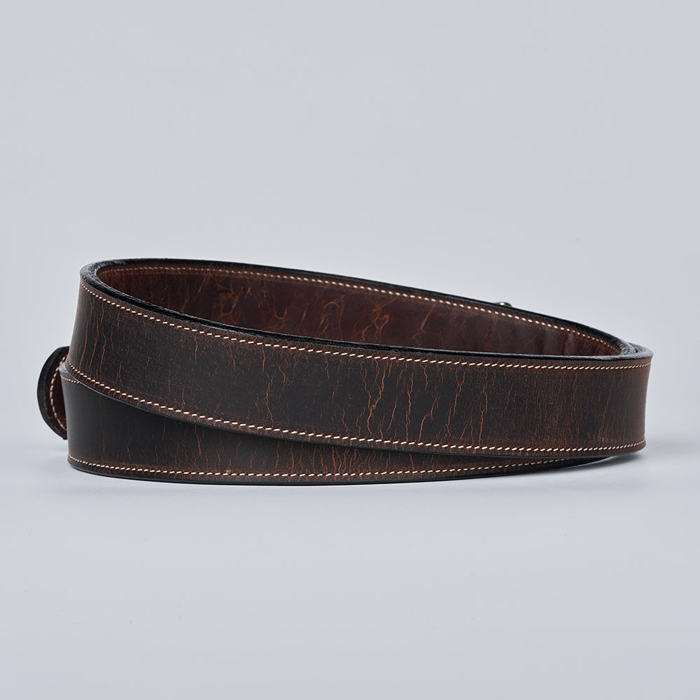 The Wyoming Bison Lined belt by Hanks Belts, shown rolled up with tan stitching and a slightly worn dark brown finish, is displayed against a plain light gray background.
