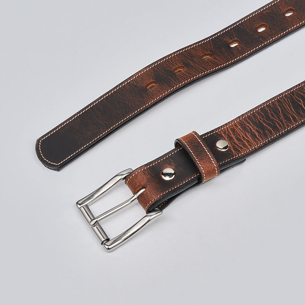The Wyoming Bison Lined by Hanks Belts is a brown bison leather belt with a silver double-prong buckle, white edge stitching, and multiple adjustment holes, shown on a light gray background and crafted in their signature style.