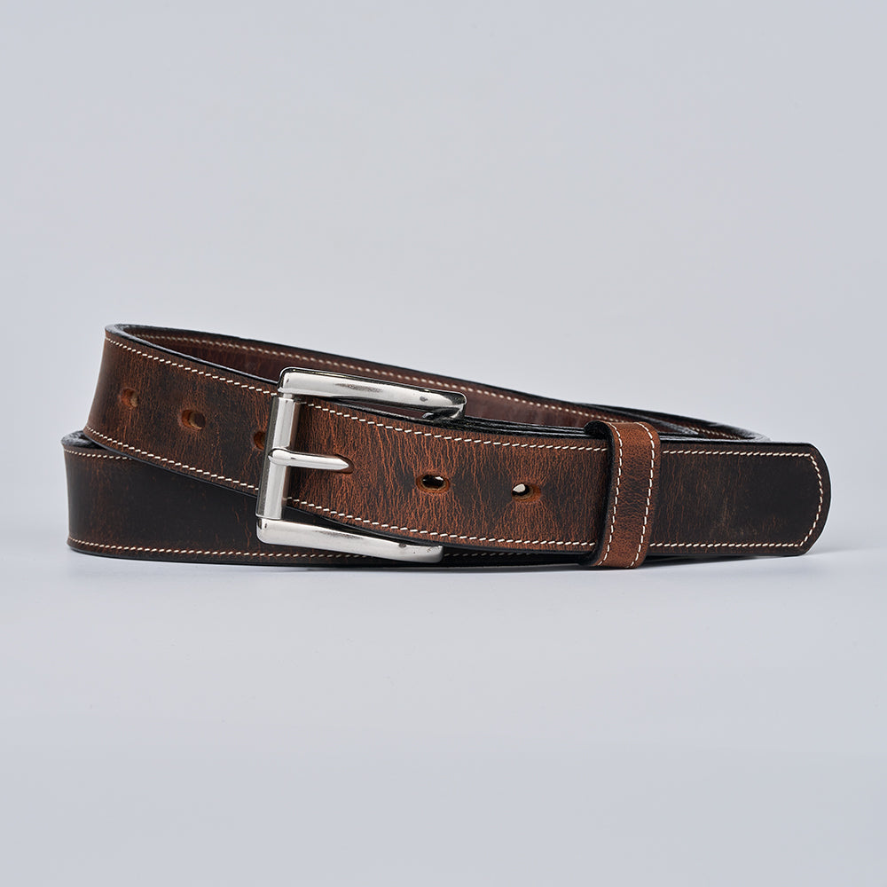 The Wyoming Bison Lined belt by Hanks Belts, featuring sturdy brown bison leather, white stitching, and a silver rectangular buckle, is coiled and displayed on a plain light gray background.