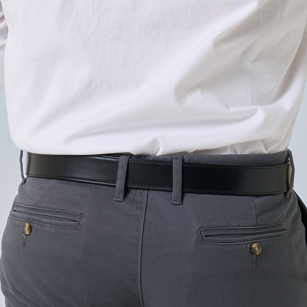 A person wears a white shirt tucked into gray pants, highlighting Hanks Belts' The Canyon vegetable-tanned leather belt around their waist and the back pockets of the pants.
