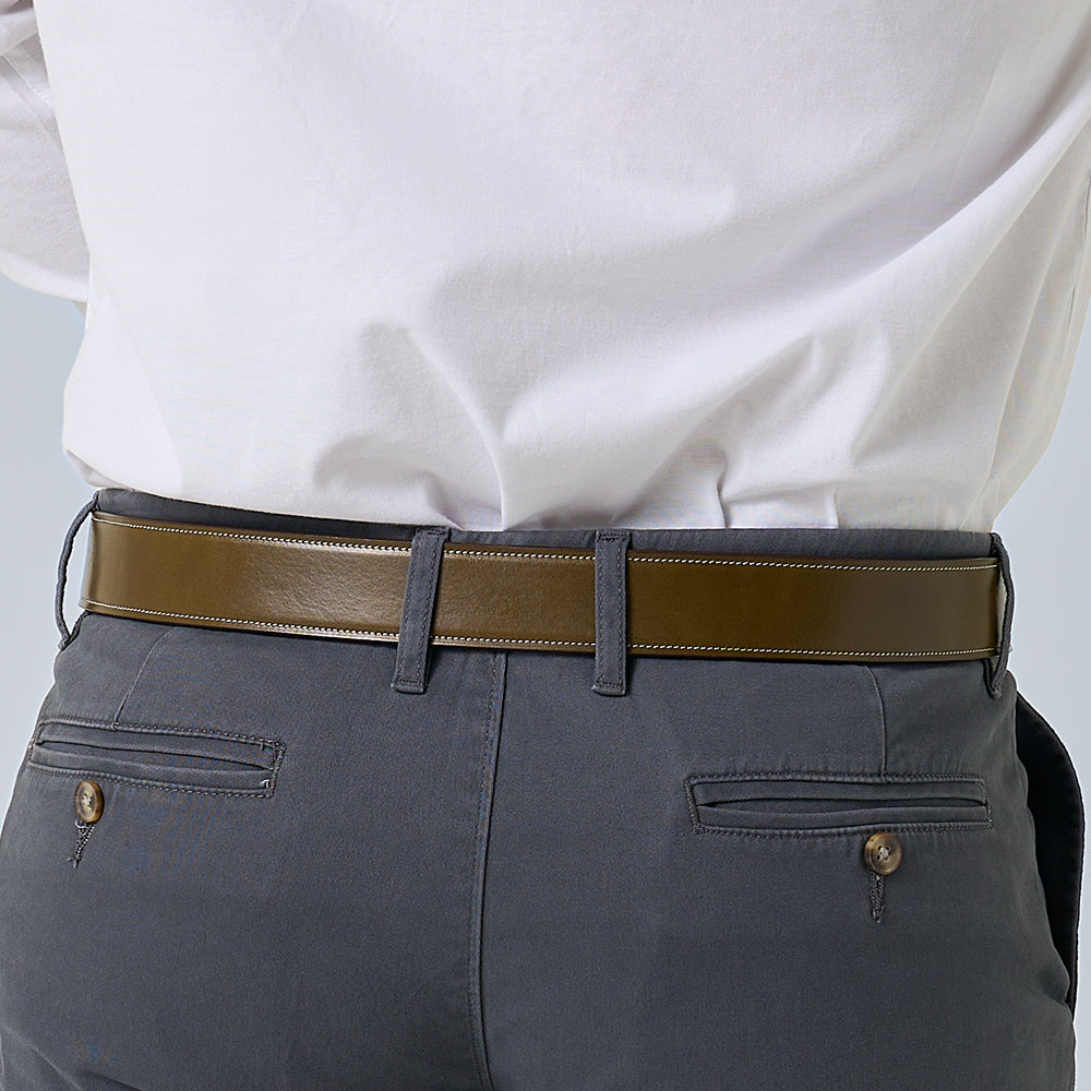 A person is shown from the back wearing a white shirt, dark gray pants with buttoned back pockets, and The Canyon—a handcrafted vegetable-tanned leather belt from Hanks Belts with matching loops.