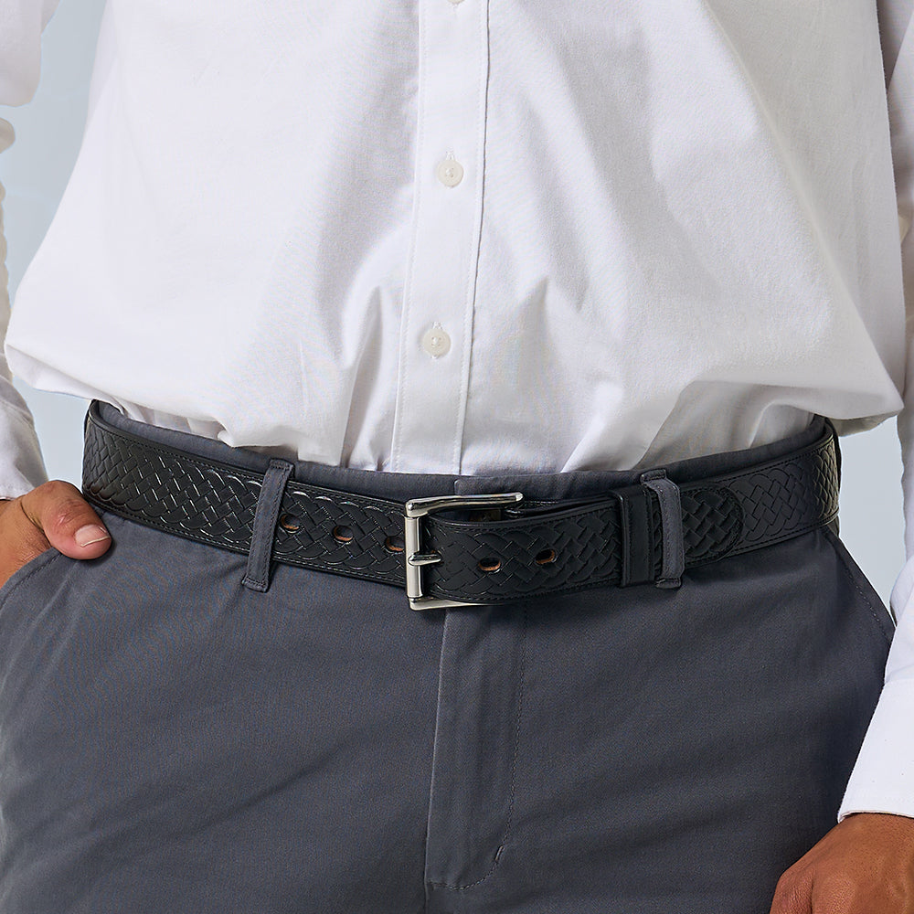 A person in a white button-up tucked into gray pants completes their look with Hanks Belts’ The Classic Basket Weave, a leather belt featuring a silver buckle.
