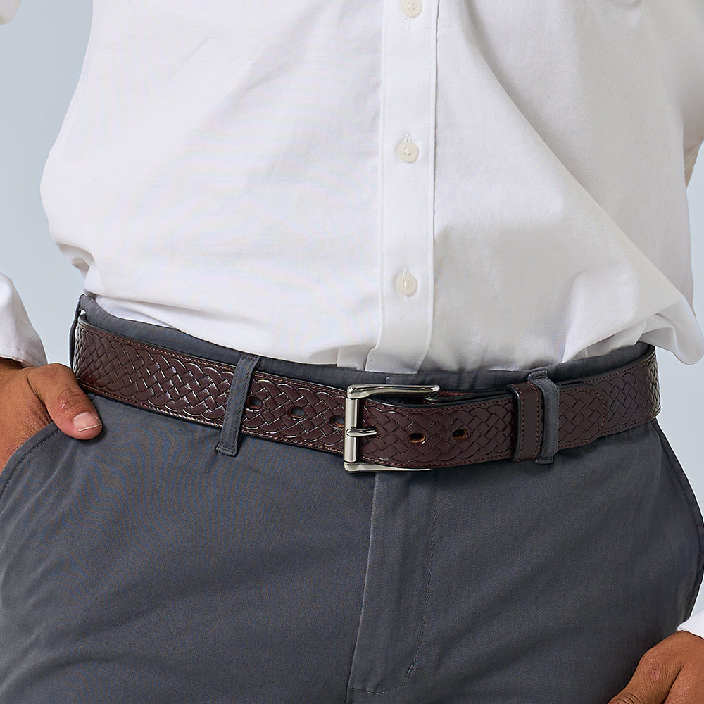 A person wearing a white button-up shirt tucked into gray pants, accessorized with Hanks Belts' The Classic Basket Weave dark brown leather belt with a silver buckle.