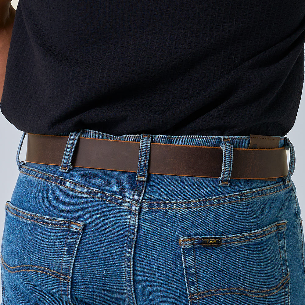 Person wearing blue jeans with Hanks Belts' The Crazy Horse retro leather belt and a dark textured shirt, shown from the back, waist down.