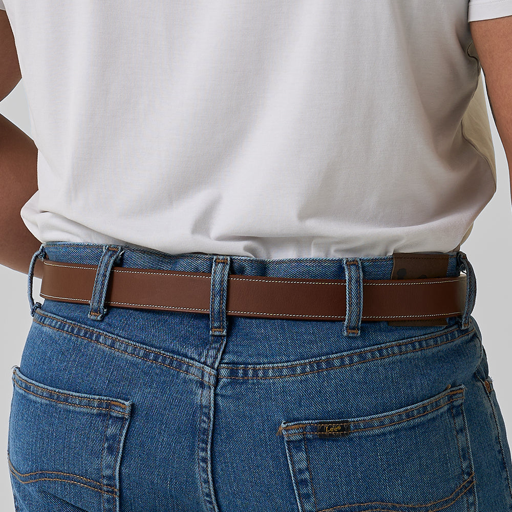 A person wearing blue jeans and The Heritage Bison belt by Hanks Belts, shown from the back with a white t-shirt tucked in—a tribute to classic American craftsmanship.