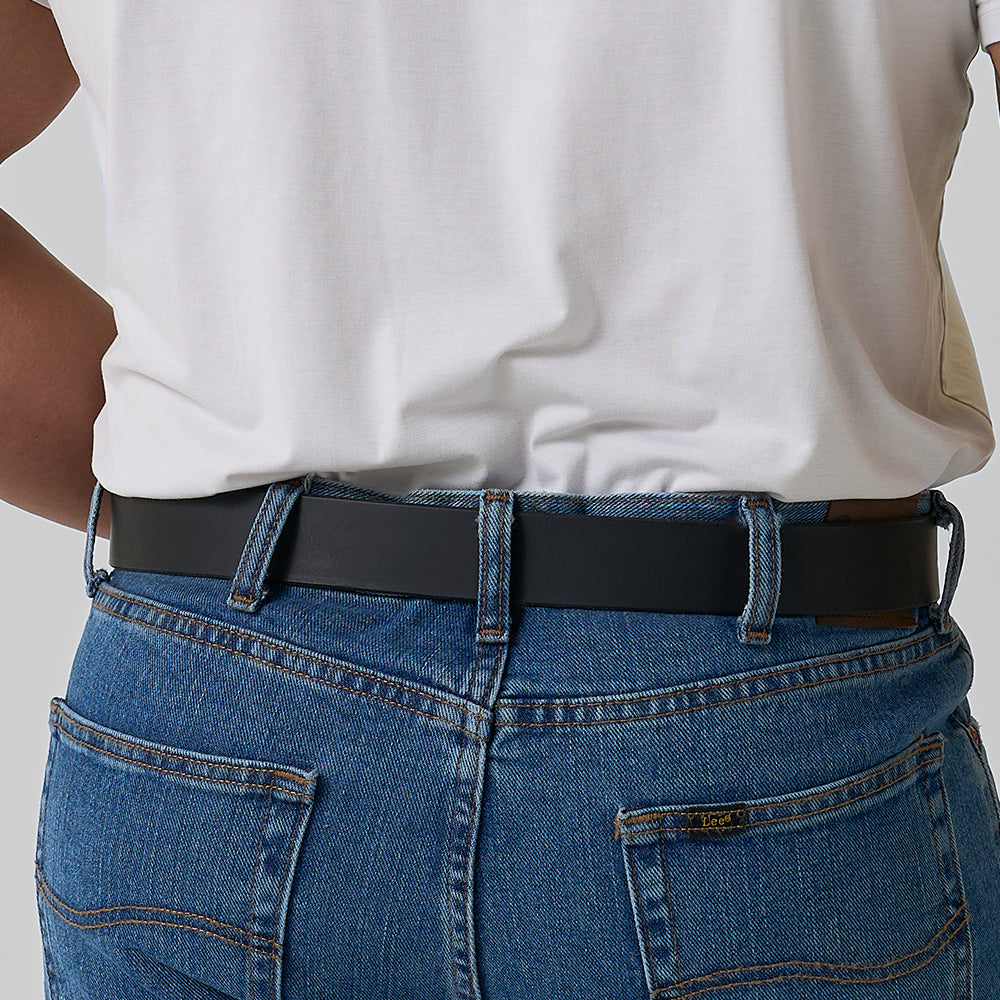 A person wearing a white T-shirt tucked into blue jeans showcases the Hanks Belts The Legend Double Prong Retro Style leather belt, viewed from the back with focus on the waist and lower back area.