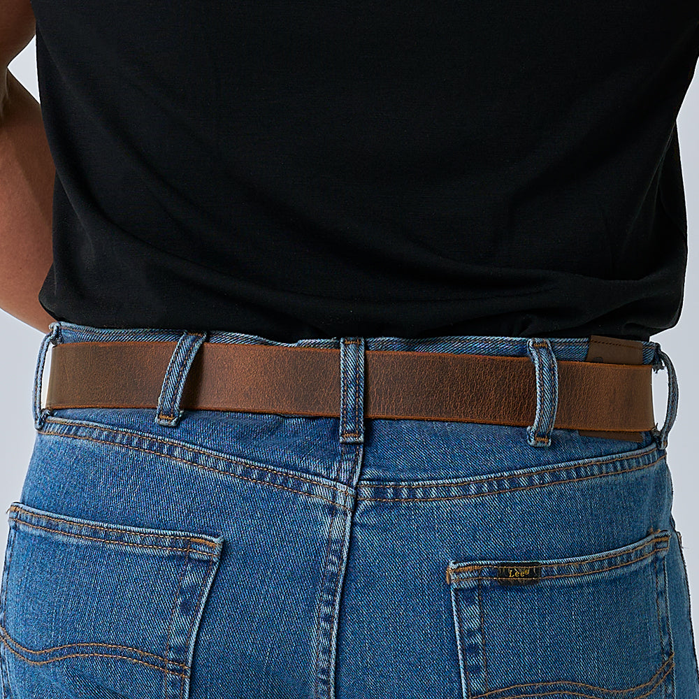 A person is wearing blue jeans and a black shirt tucked in, showcasing the Hanks Belts Legend Double Prong Retro Style belt; the image highlights their lower back and waist.