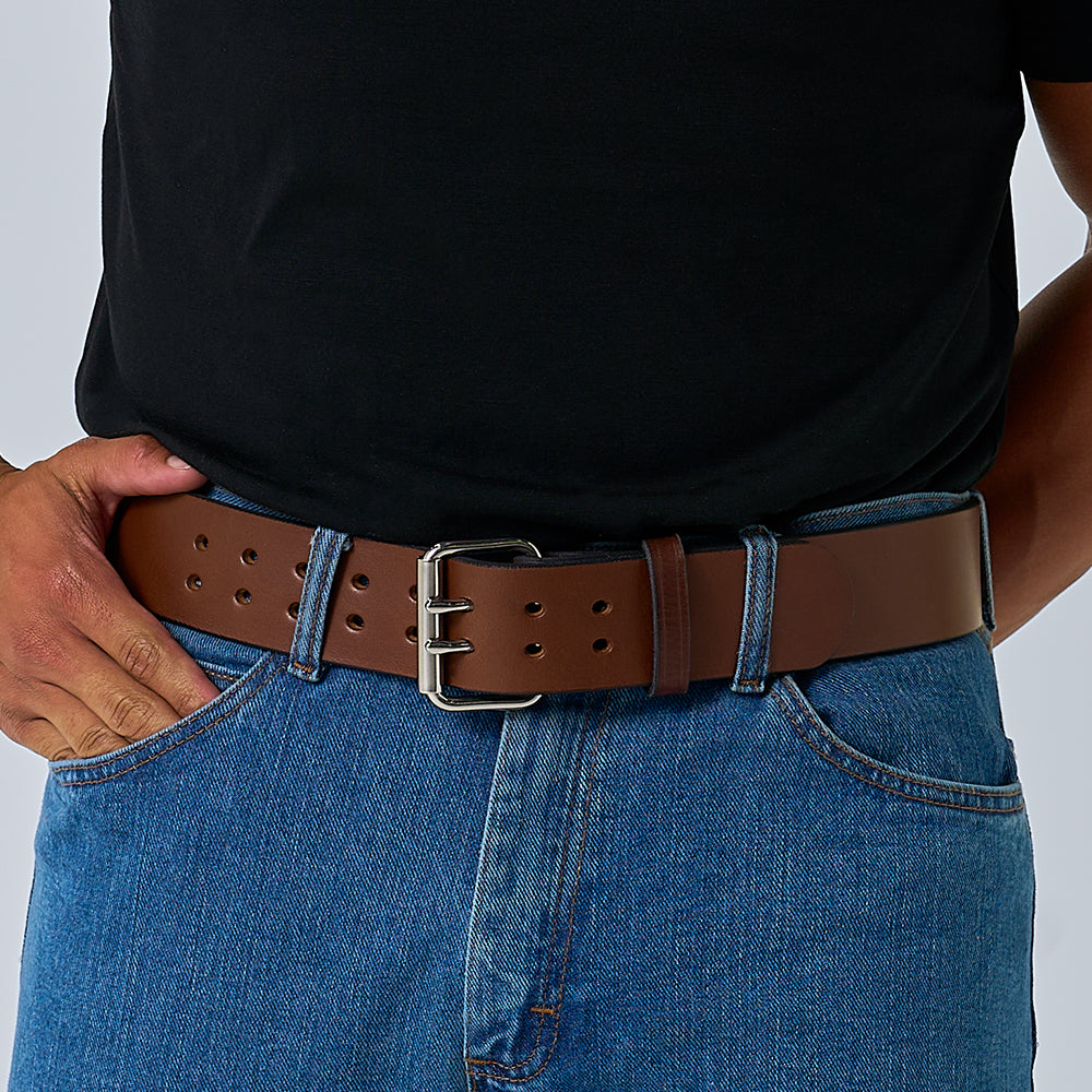 A person wearing a black shirt tucked into blue jeans with Hanks Belts’ “The Marshall” 2" wide gun belt, featuring a large silver buckle. One hand rests in a front pocket.