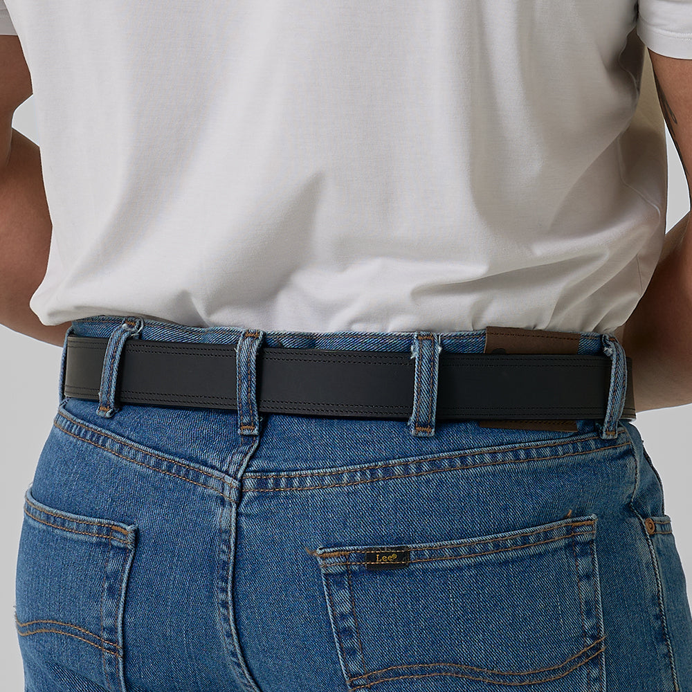 Person wearing a black belt with blue jeans on a neutral background