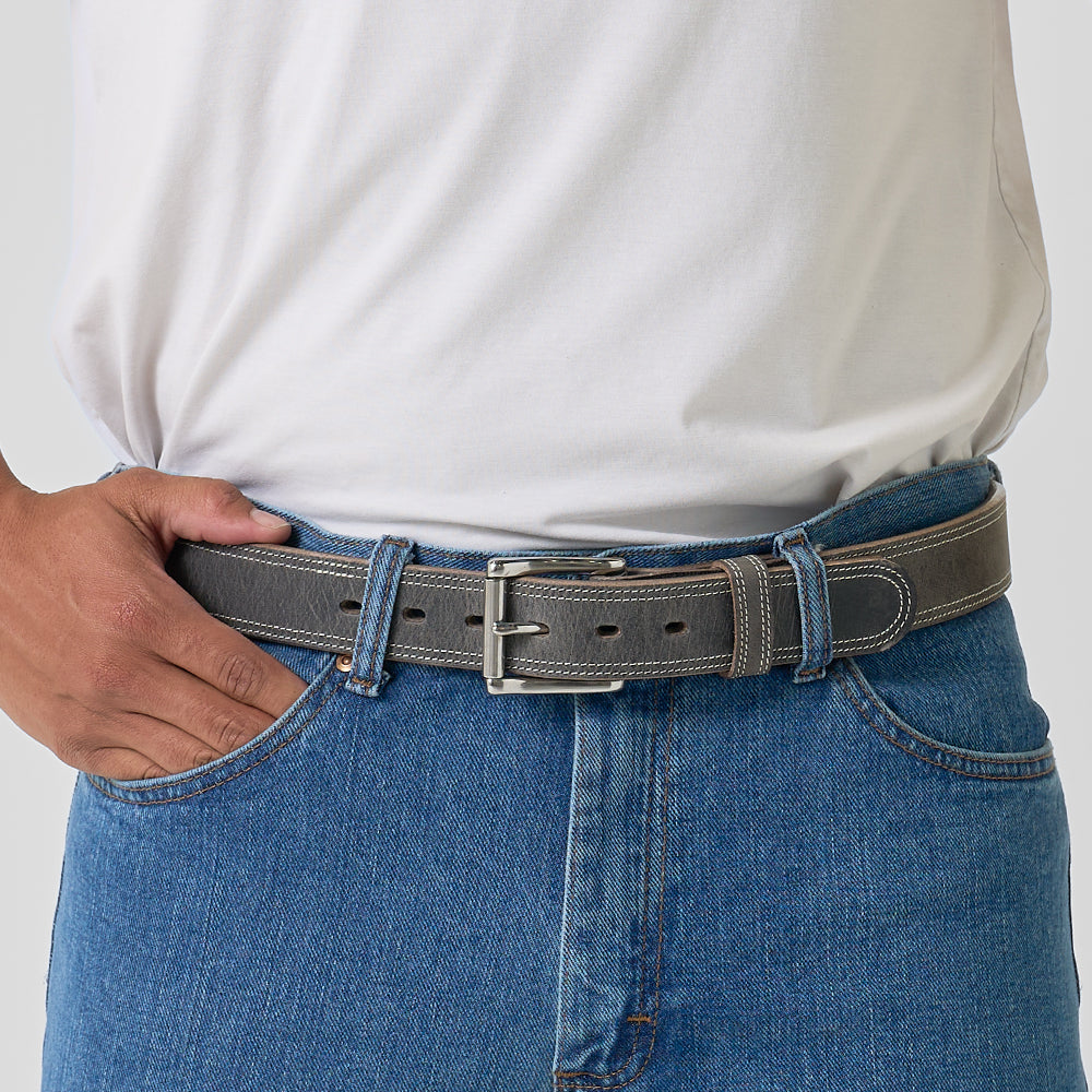 Person wearing a gray belt with a white shirt and blue jeans on a light gray background