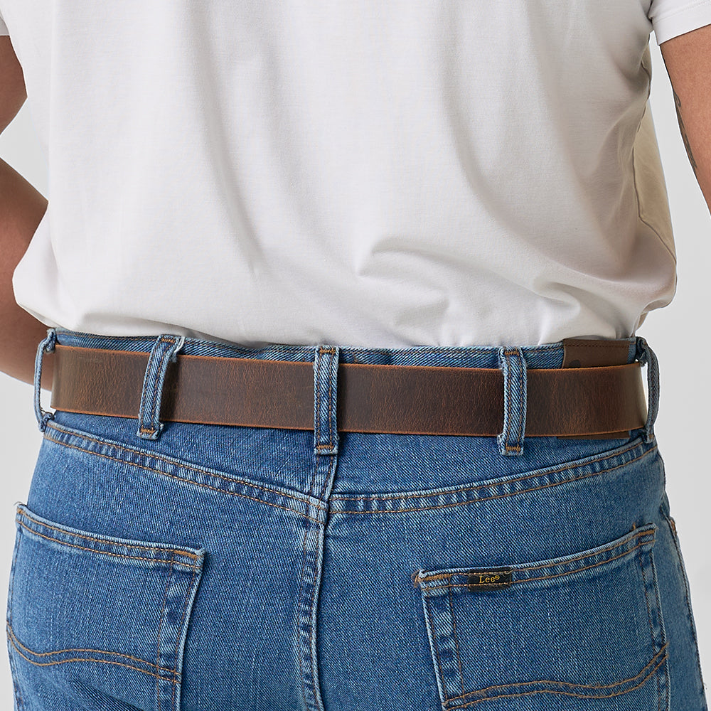 A person shown from the back at waist level wears a white shirt tucked into blue jeans with The Relic Retro Style belt by Hanks Belts.
